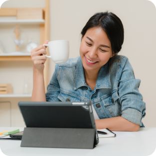 
	Asian women looking for her next job opportunity on ipad with a cup in her hand while smiling 
