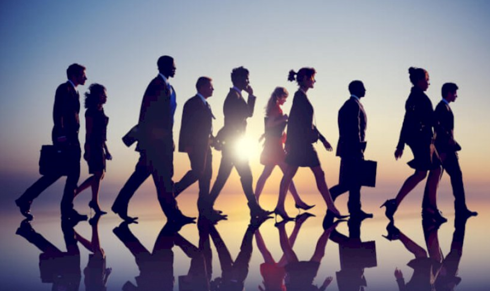 
	Group of businesspeople waking together on the water with the sun behind them shinning on them
